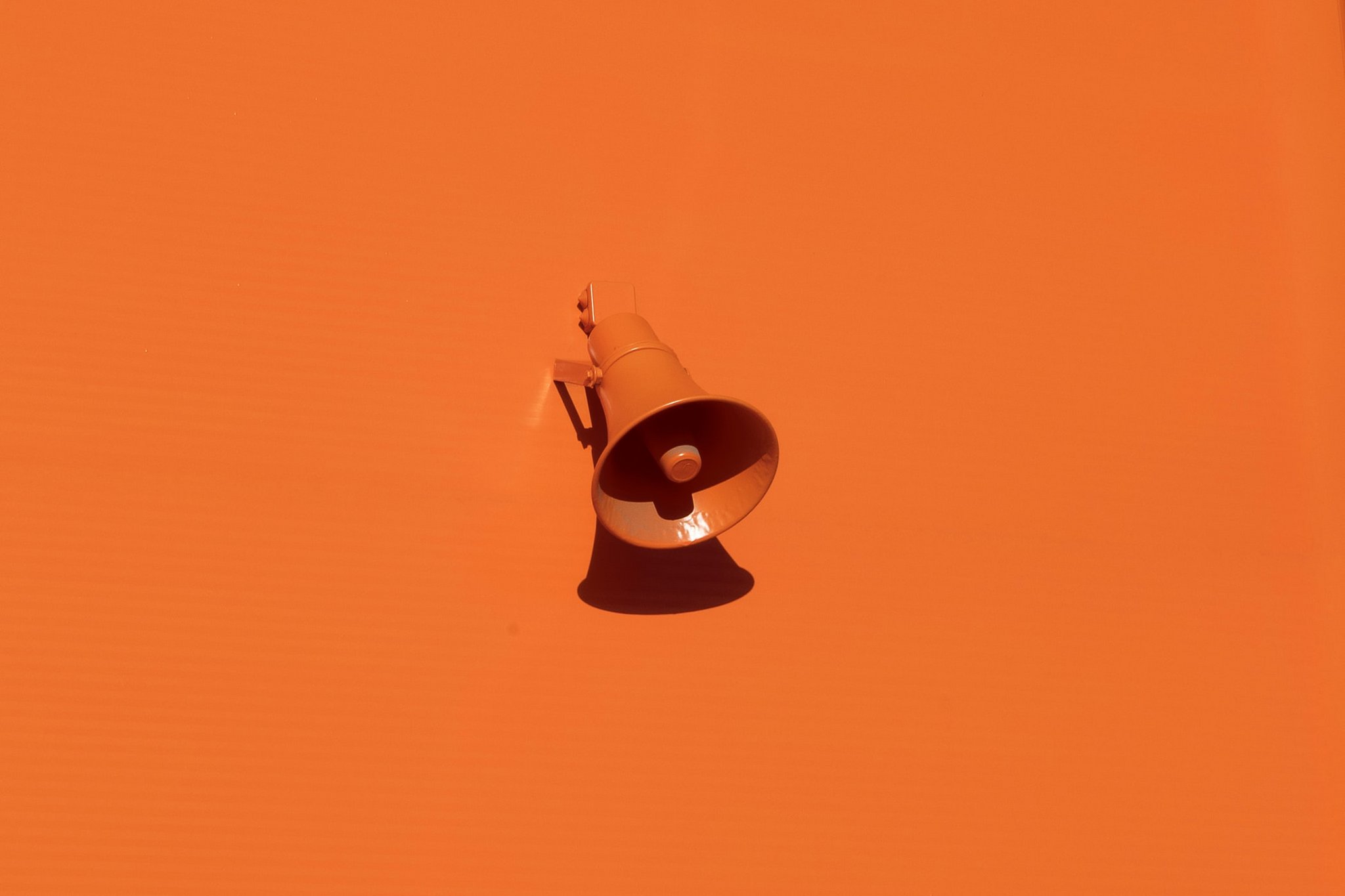Lautsprecher Das Bild zeigt eine orangene Wand mit einem Lautsprecher in der gleichen Farbe